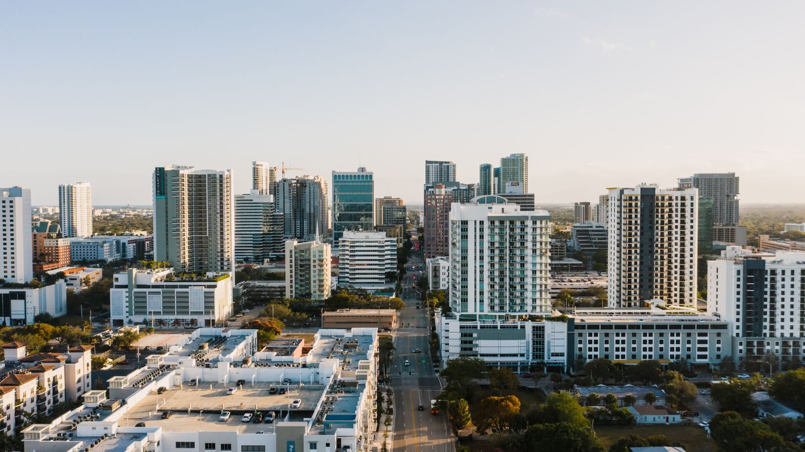 Aerial view of downtown high-rise towers and apartment buildings along a straight avenue in late-afternoon light